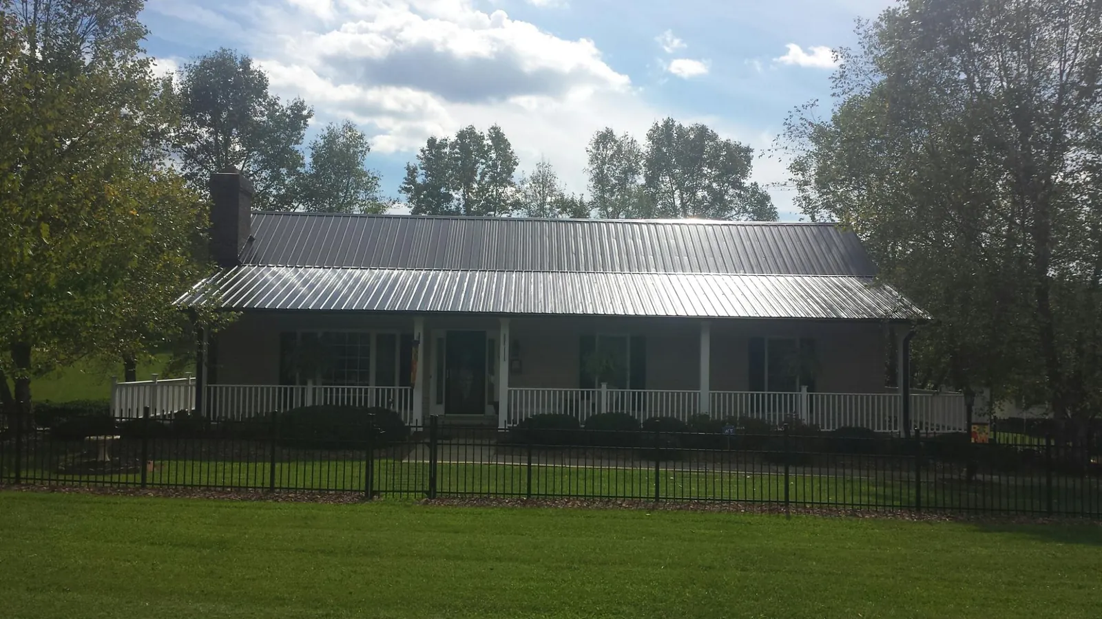 Gray metal roof on a brick ranch with a full width front porch — Gutter Guard Installation work by our crew in La Fayette